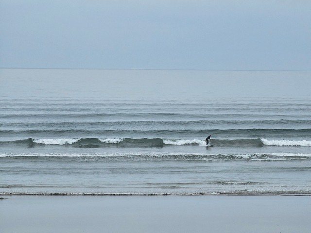 Surfer riding a wave in the shallows as a set breaks on the outside